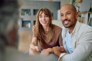Young couple smiling and shaking hands with a financial adviser